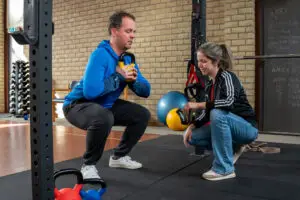 Man sport onder begeleiding van een fysiotherapeut