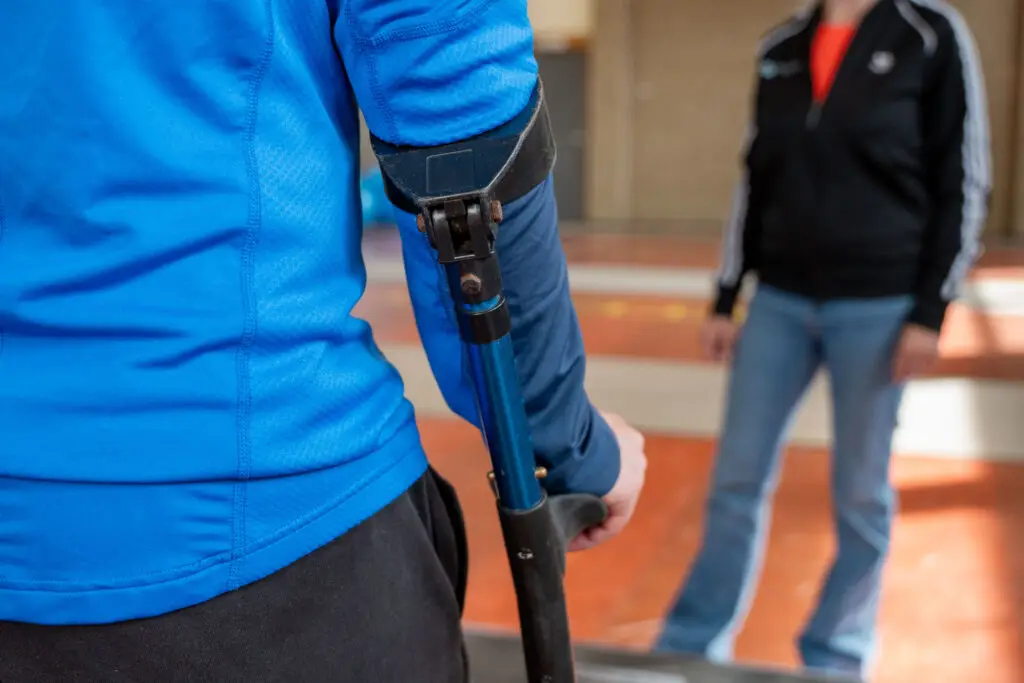 Patiënt met nieuwe knie of nieuwe heup wordt begeleidt door fysiotherapeut door middel van het leren lopen met elleboogkrukken