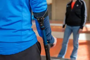 Patiënt met nieuwe knie of nieuwe heup wordt begeleidt door fysiotherapeut door middel van het leren lopen met elleboogkrukken