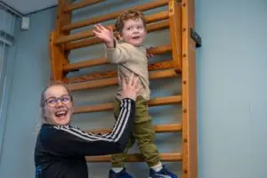 Peuter klimt bij peutergym onder begeleiding kinderfysiotherapeut